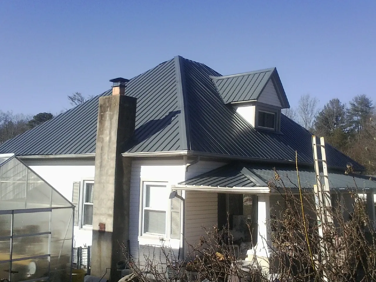 Dark blue standing seam metal roof on a white farmhouse with dormer — Slate & Tile Roof Repair by Roofing Brothers in Lavallette