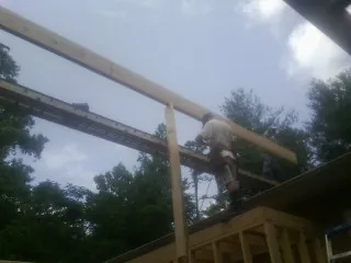 Carpenter setting a ridge beam over a new addition frame — Ice Dam Removal by Roofing Brothers in Lavallette