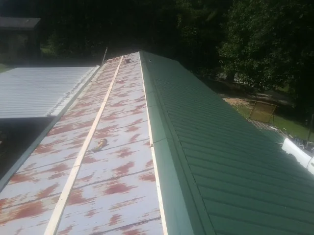 Old rusted panels beside newly installed green metal roofing — Wind Damage Roof Repair by Roofing Brothers in Lavallette