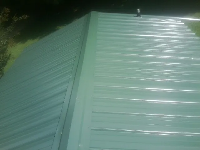New green metal panels meeting at the ridge of a roof — Flat Roof Repair work by our crew in Lavallette