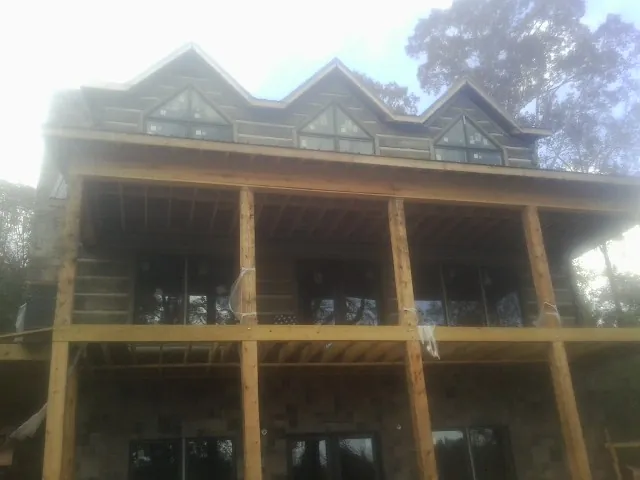 Dormers and porch framing on a large log home under construction — Roof Coating work by our crew in Lavallette