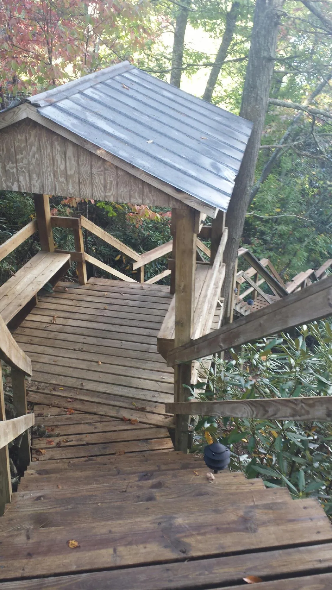 Metal roofed shelter over wooden steps on a wooded walkway in Lavallette