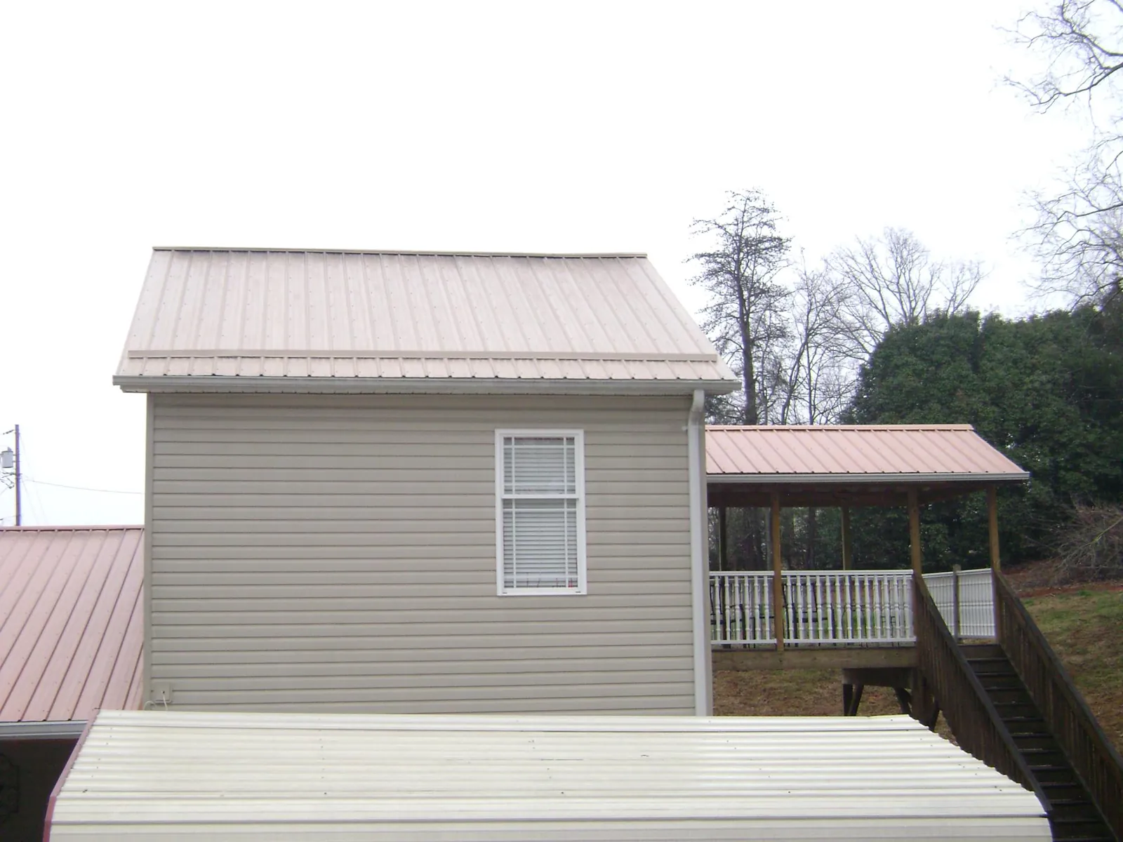 Tan metal roofs on a two story addition and attached porch, from a Roof Replacement job in Lavallette